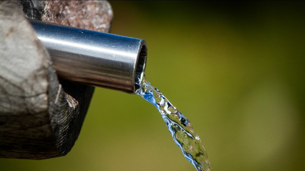 a close up of a metal faucet with water coming out of it